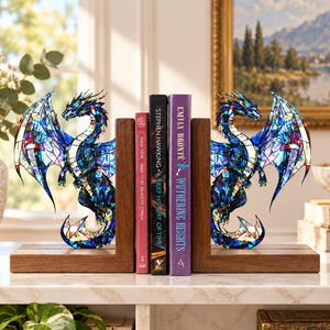 May include: A pair of bookends featuring two dragon figures with a stained-glass style finish in shades of blue, purple, and teal. The dragons are mounted on rectangular wooden bases, supporting three books titled Voyage au centre de la Terre, A Brief History of Time, and Wuthering Heights.