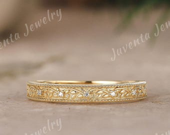 May include: A yellow gold band ring featuring an intricate engraved leaf and vine pattern along the outer surface, accented with small, evenly spaced round clear stones. The text Juventa Jewelry is visible in the background.