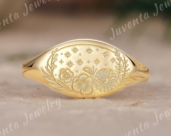 Könnte beinhalten: Ein goldfarbener Ring mit ovaler Oberfläche, verziert mit einem gravierten Blumen- und Sternmuster. Der Ring ist von Juventa Jewelry.