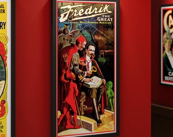 May include: Framed vintage poster featuring "Fredrik the Great, World Renowned Magician." The artwork depicts a magician with a key, surrounded by devils and goblins. The poster has a black frame and is displayed on a red wall.