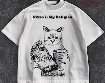 Peut inclure: T-shirt blanc avec un motif noir d'un chat tenant une part de pizza et une tasse de café. Le texte "Pizza is My Religion" est imprimé au-dessus du chat. Le t-shirt a un col montant et des manches courtes.