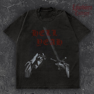 Puede incluir: Camiseta gris oscuro con las palabras "HELL DEAD" en letras góticas rojas. La camiseta presenta un gráfico de una espada y una mano sosteniendo un cigarrillo. El logotipo de la marca "Lowborn Culture" está en la esquina superior derecha.