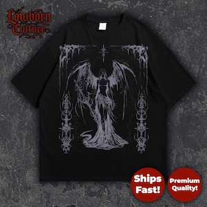 Op de afbeelding: Zwart T-shirt met een gotische illustratie van een gevleugelde figuur in een vloeiende jurk, met een slang. Het ontwerp is in grijs en wit. Het shirt heeft de tekst "Lowborn Culture" linksboven.
