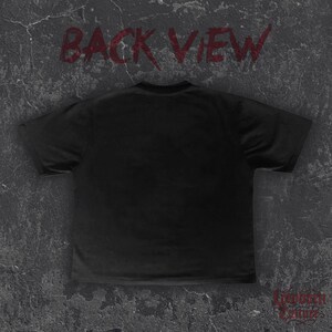 May include: Black t-shirt with the words "BACK VIEW" in red, stylized text across the top. The bottom right corner features the text "Forbidden Culture" in a decorative font. The shirt is displayed on a textured, grey surface.
