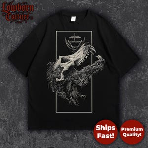 May include: Black t-shirt with a detailed illustration of a wolf skull, set within a white rectangular frame. The shirt features the text "Lowborn Culture" in a gothic font. The wolf skull is depicted with an open mouth.