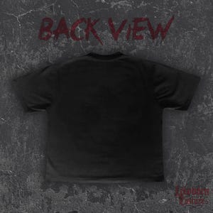 Op de afbeelding: Zwart T-shirt met de woorden "BACK VIEW" in rode, gestileerde tekst bovenaan. De rechter benedenhoek bevat de tekst "Forbidden Culture" in een decoratief lettertype. Het shirt wordt gepresenteerd op een getextureerde, grijze achtergrond.
