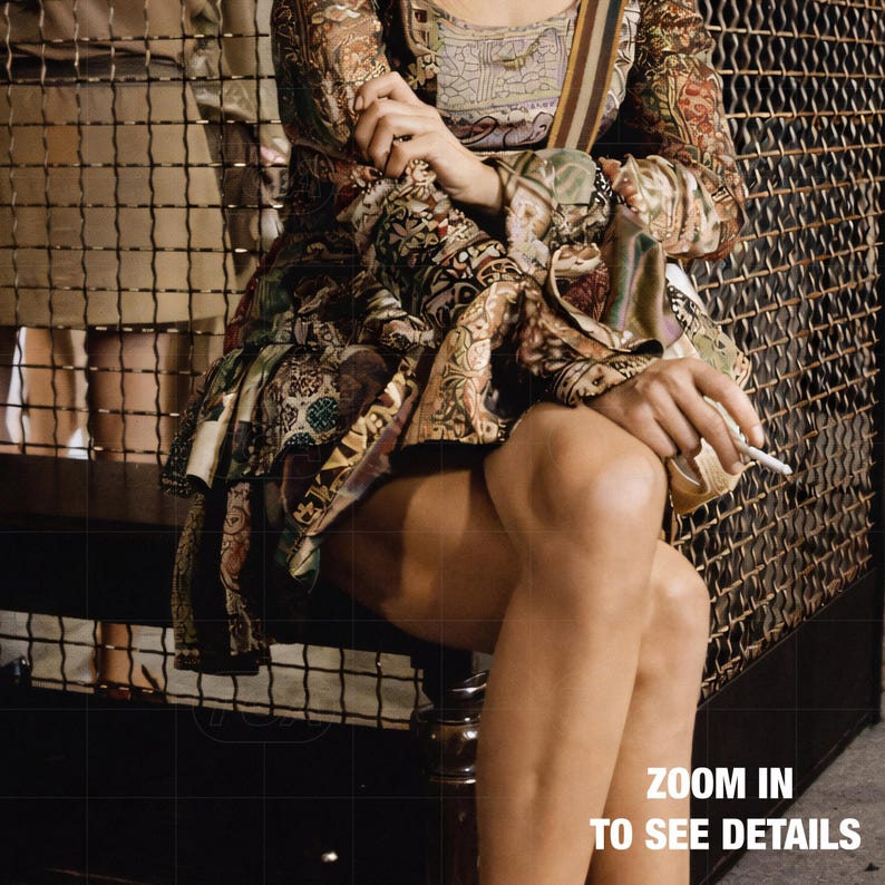 A woman in a colorful, patterned dress sits on a bench, holding a cigarette in her hand.