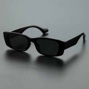 May include: Black rectangular sunglasses with dark lenses. The sunglasses have a thick, solid frame and curved temples. The design is simple and modern, suitable for various styles.