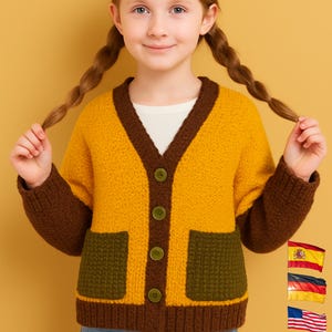 Może przedstawiać: Musztardowy kardigan z brązowymi wykończeniami i kieszeniami. Kardigan z dekoltem w serek jest zapinany na zielone guziki. Rękawy i wykończenia są brązowe. Noszony na białej koszulce i niebieskich dżinsach.