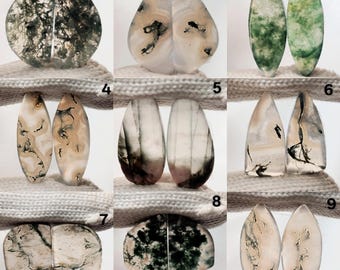 May include: A collection of nine pairs of polished gemstones, each with unique patterns and colors. The stones vary in shape, including round, teardrop, and oval. Colors range from green and white to beige and black, showcasing natural veining.