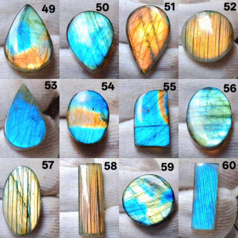 Pu&ograve; includere: Una collezione di pietre preziose di labradorite lucidata in varie forme, tra cui a goccia, ovale e rotonda. Le pietre mostrano lampi iridescenti di blu, arancione e giallo, con una superficie liscia e lucida. Ogni pietra &egrave; unica nel colore e nel motivo.