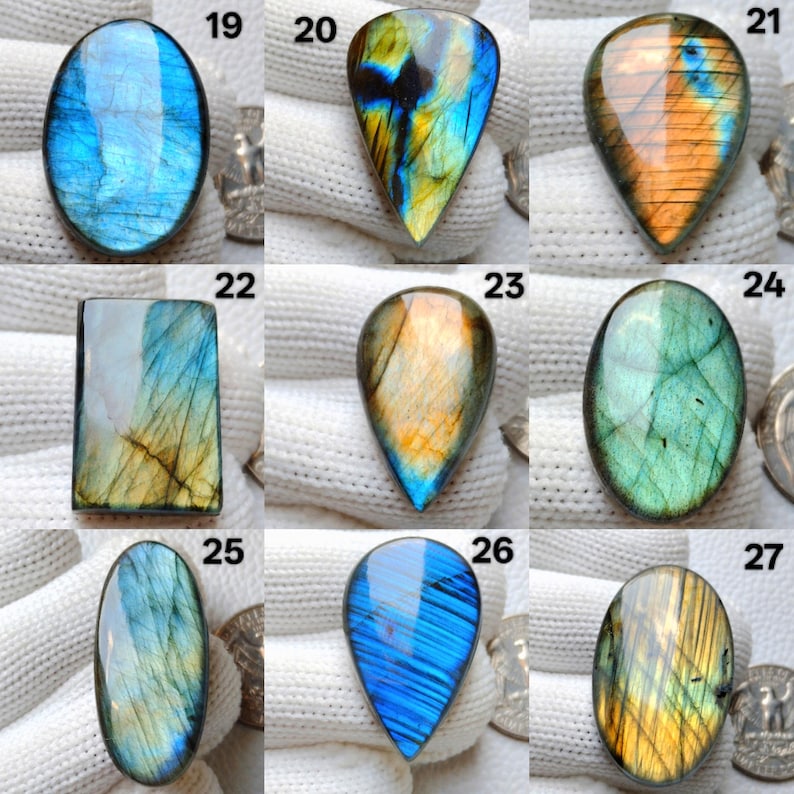 May include: A collection of polished labradorite gemstones in various shapes, including oval, teardrop, and rectangular. The stones display iridescent flashes of blue, green, yellow, and orange. Each stone is unique, showcasing natural patterns and colors.