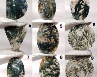 May include: Nine moss agate gemstones in various shapes, including oval, round, and triangular. The stones display a mix of green, white, and brown patterns, resembling natural landscapes. Each stone is held against a white background.