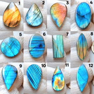 May include: Twelve polished labradorite gemstones in diverse shapes, such as teardrop, oval, and rectangular. The stones exhibit iridescent flashes of blue, gold, and green, with some featuring striped patterns. The gemstones are presented on a white surface.