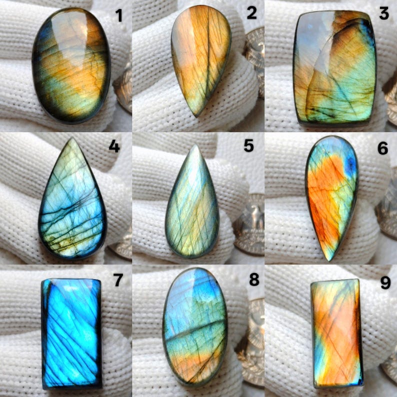 May include: Nine polished labradorite gemstones in various shapes: oval, teardrop, and rectangular. The stones display iridescent colors of blue, green, orange, and yellow. Each stone is unique, showcasing natural patterns and color variations.