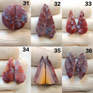 May include: A collection of six pairs of polished gemstones, each cut into different shapes. The stones display a mix of red, blue, and cream colors with unique patterns. The gemstones are numbered 31 through 36.