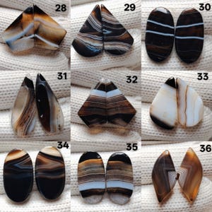 May include: A selection of polished agate stones in diverse shapes, such as teardrop, oval, and geometric forms. The stones display a blend of brown, white, and black banding patterns. Each pair is numbered for identification.
