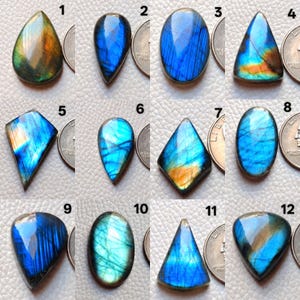 May include: A collection of twelve polished labradorite gemstones in various shapes, including teardrop, oval, and triangular. The stones display iridescent flashes of blue, green, and orange, with a polished surface. Each stone is unique.