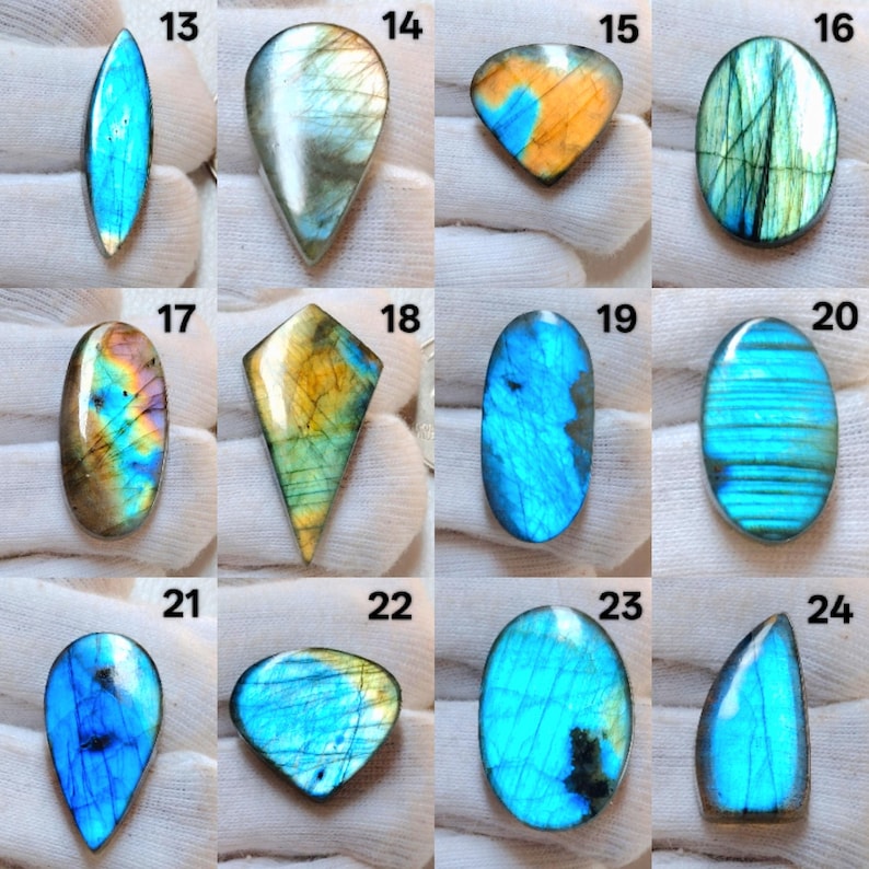 Pu&ograve; includere: Una collezione di pietre preziose di labradorite lucidata in varie forme, tra cui ovale, a goccia e a scudo. Le pietre mostrano lampi iridescenti di blu, verde, giallo e arancione. Ogni pietra &egrave; numerata.