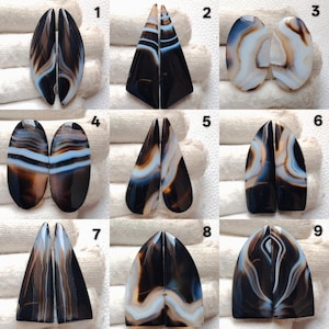 Pode incluir: Nove pares de pedras preciosas de ágata polida em várias formas, incluindo ovais, triangulares e em forma de gota. As pedras apresentam uma mistura de padrões de bandas pretas, castanhas, brancas e azuis. Cada par é dividido ao meio, mostrando os desenhos simétricos.