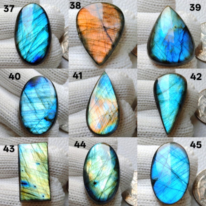 May include: Nine polished labradorite gemstones in various shapes, including oval, teardrop, and rectangular. The stones display iridescent flashes of blue, green, and orange. Each stone is numbered for identification.