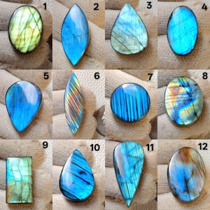 May include: A collection of twelve polished labradorite gemstones in various shapes, including oval, teardrop, and rectangular. The stones display iridescent flashes of blue, green, and yellow, with some showing a mix of colors. Each stone is unique, showcasing natural patterns.