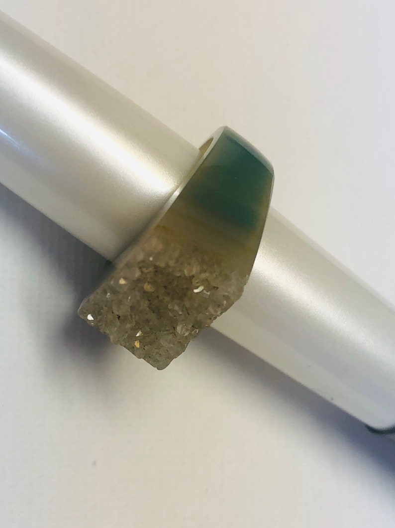 K&ouml;nnte beinhalten: Ein silberner Ring mit einem gr&uuml;nen Stein und einem Cluster aus klaren Kristallen.