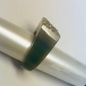 K&ouml;nnte beinhalten: Ein silberner Ring mit einer strukturierten, rauen Oberfl&auml;che. Der Ring liegt auf einem wei&szlig;en Hintergrund.