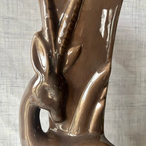 May include: A brown ceramic vase shaped like an antelope with a glossy finish.