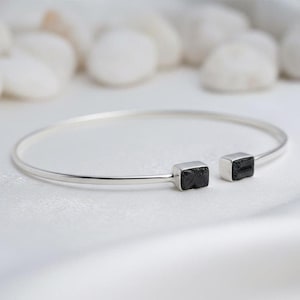 Könnte beinhalten: Eine weiße Keramik-Tasse mit schwarzem Henkel und dem Text "But First, Coffee" in schwarzer, handschriftlicher Schrift. Die Tasse hat wahrscheinlich ein Fassungsvermögen von 325-445 ml, ideal für ein Morgengetränk.