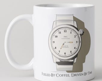 May include: White ceramic mug featuring a watch design with the text "IWC SCHAFFHAUSEN" and "MARK XX AUTOMATIC". The mug also has the phrase "FUELED BY COFFEE, DRIVEN BY TIME" printed on it.