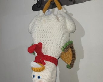May include: A handmade, upside-down crochet snowman with a red scarf, orange beak, and blue eyes. The snowman has a taco attached to its side and is suspended by yellow crochet handles.