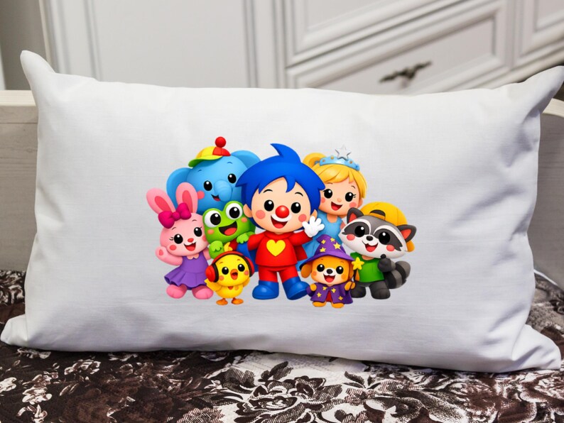 May include: A rectangular white pillow featuring a colorful graphic print of a group of cartoon characters, including a central figure with blue hair and a red outfit, surrounded by a pink rabbit, a blue elephant, a green frog, and other animals.