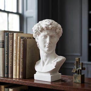 May include: A white ceramic mug with a black handle and the text "But First, Coffee" in a bold, black font. The mug is set against a blurred background, suggesting a cozy setting.