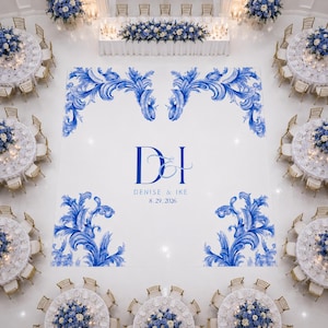 Puede incluir: Vista aérea de una recepción de boda. El suelo blanco presenta diseños florales azules y los nombres "Denise & Ike" con la fecha "8.29.2026". Mesas redondas con centros de mesa florales y sillas doradas rodean la pista de baile.
