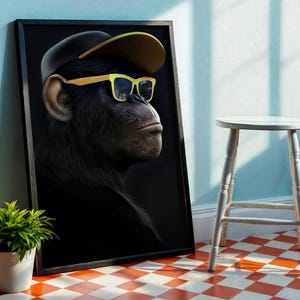 Peut inclure: Impression d'art encadrée représentant un chimpanzé portant une casquette noire et des lunettes à monture jaune. Le portrait du chimpanzé est présenté sur un fond sombre. L'œuvre est exposée à côté d'un petit tabouret blanc et d'une plante en pot.