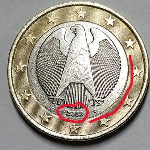 Può includere: Primo piano di una moneta da un euro. La moneta presenta un'aquila argentata dettagliata al centro, circondata da un anello dorato con stelle. L'anno "2002" è visibile sulla moneta.