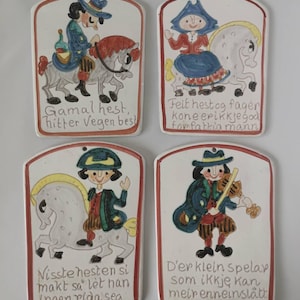 Może przedstawiać: Cztery prostokątne ceramiczne płytki ścienne z zaokrąglonymi górnymi krawędziami, każda z ręcznie malowanymi ilustracjami postaci i koni oraz norweskim tekstem. Wzory przedstawiają jeźdźca, osobę na koniu oraz muzyka grającego na skrzypcach.