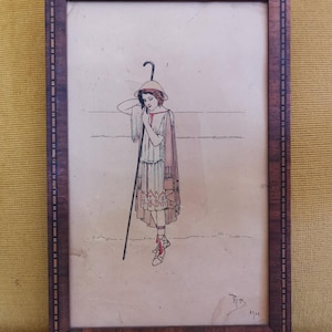 Peut inclure: Une illustration encadrée représentant une personne vêtue d'une tunique claire avec des accents rouges, un chapeau à larges bords et des chaussures à lacets, tenant un long bâton. L'œuvre est dans un cadre en bois rectangulaire à bordure géométrique.