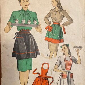 May include: Vintage Du Barry Patterns sewing pattern featuring illustrations of aprons. The aprons are in various styles and colors, including black, orange, green, and red. The pattern is marked "Medium" and priced at 15¢.