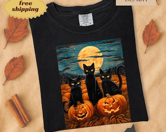 May include: Black t-shirt featuring a Halloween-themed graphic. The graphic depicts three black cats sitting on carved pumpkins under a full moon. The shirt is labeled "Color BLACK".