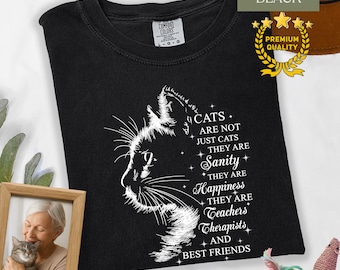 May include: Black t-shirt with a white cat silhouette and text that reads "Cats are not just cats, they are sanity, happiness, teachers, therapists, and best friends." The shirt has a crew neck and short sleeves.