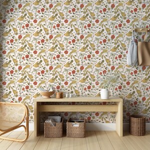 May include: Wallpaper featuring a repeating pattern of yellow birds, red flowers, and green foliage on a white background. The scene includes a light wood console table, two woven storage baskets, a white vase, and a hanging beige tote bag.