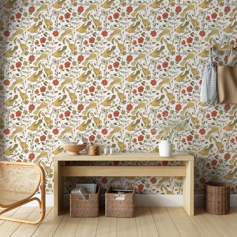 May include: Wallpaper featuring a repeating pattern of yellow birds, red flowers, and green foliage on a white background. The scene includes a light wood console table, two woven storage baskets, a white vase, and a hanging beige tote bag.