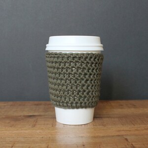 May include: A green crocheted coffee cup cozy. The cozy is made with a simple stitch pattern and is a great way to keep your hands warm while enjoying your favorite beverage.