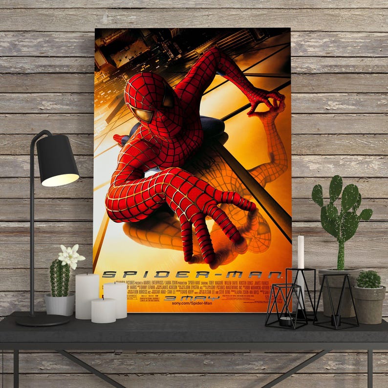 May include: A framed movie poster for Spider-Man. The poster features the superhero in a red and blue suit, with a cityscape background. The title "SPIDER-MAN" is prominently displayed at the bottom.