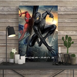 May include: A framed movie poster for Spider-Man 3. The poster features two versions of Spider-Man: one in a red and blue suit and the other in a black suit. The background shows a cityscape with a sunset.