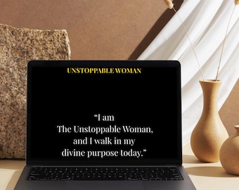 May include: A laptop displays the text "UNSTOPPABLE WOMAN" and a motivational quote. The laptop is on a light surface, with a decorative vase and a stone in the background. The quote reads, "I am The Unstoppable Woman, and I walk in my divine purpose today."