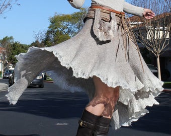 May include: A woman wearing a flowing, light gray skirt with a brown leather belt and fringe detail. She is wearing brown leather boots with high heels.