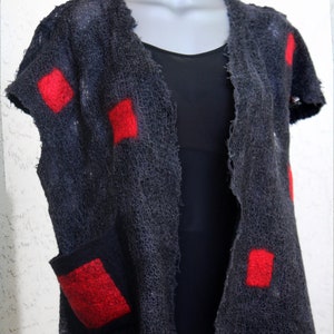 May include: A dark gray, open-front vest with short sleeves and a single pocket. The vest features several bright red square patches. The garment is displayed on a mannequin.